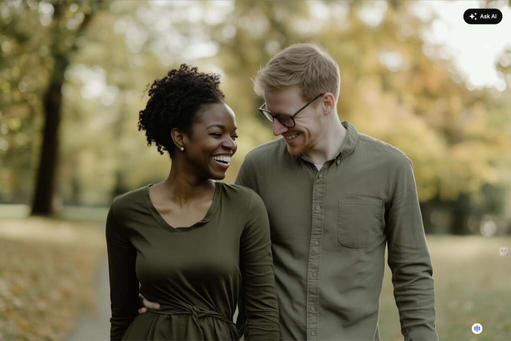 Interracial couple laughing and walking together in an autumn park, illustrating the warmth of turning toward each other in an emotionally safe relationship